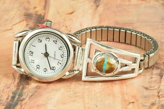 Genuine Boulder Turquoise set in Sterling Silver Watch Tips. Ladies quartz watch with expandable watch band. The cabochons are Boulder Turquoise, you can see the veins of Turquoise running through the host rock. The Boulder Turquoise Mine is located in northeast Nevada. It was discovered in 1970 by a Shoshone sheep herder. Production is small due to the remote location and winter weather. Boulder Turquoise is valued for both it's beauty and rarity. Every stone is unique. Created by Navajo Artist Freddy Charley. Signed by the artist.